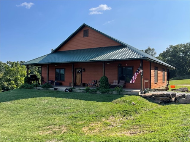 back of property featuring covered porch and a lawn