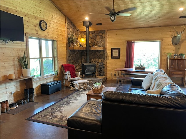 living room featuring wood walls, a wood stove, lofted ceiling, wood ceiling, and ceiling fan