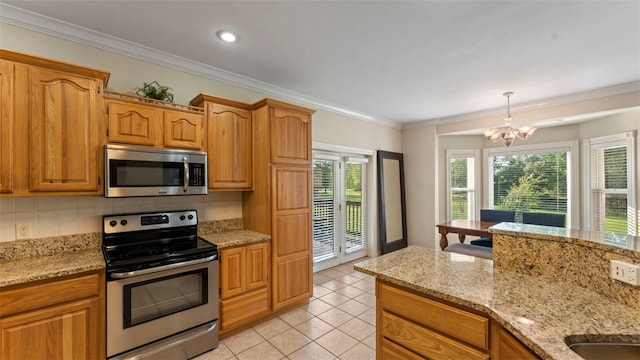 kitchen with appliances with stainless steel finishes, an inviting chandelier, tasteful backsplash, and a healthy amount of sunlight