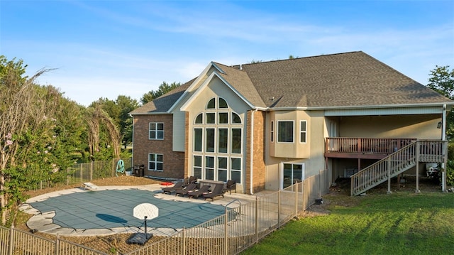 rear view of house with a swimming pool side deck, a lawn, and a patio