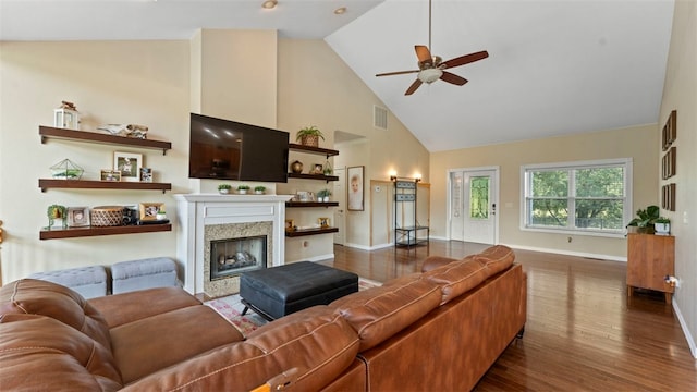 living room featuring a premium fireplace, dark hardwood / wood-style flooring, high vaulted ceiling, and ceiling fan