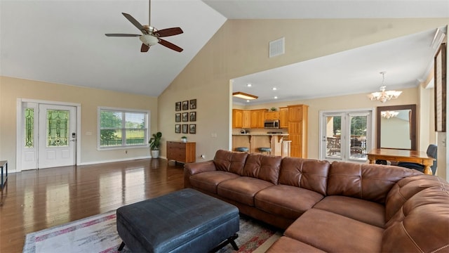 living room with dark wood-type flooring, ceiling fan with notable chandelier, and high vaulted ceiling