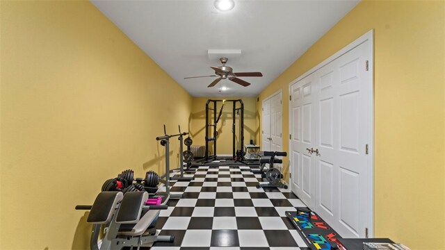 exercise room with dark tile patterned floors and ceiling fan