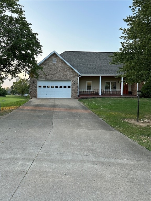 view of front facade featuring a garage, a porch, and a lawn