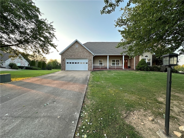 view of front of house with a garage, a porch, and a yard