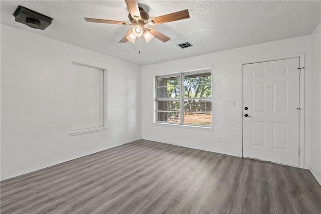 unfurnished room featuring ceiling fan, visible vents, a textured ceiling, and wood finished floors