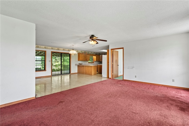 unfurnished living room with a textured ceiling, ceiling fan with notable chandelier, and light tile patterned flooring