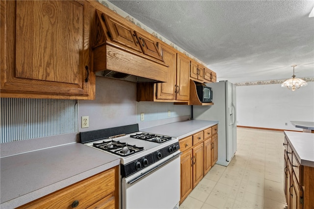 kitchen with a textured ceiling, white appliances, custom range hood, a notable chandelier, and light tile patterned flooring