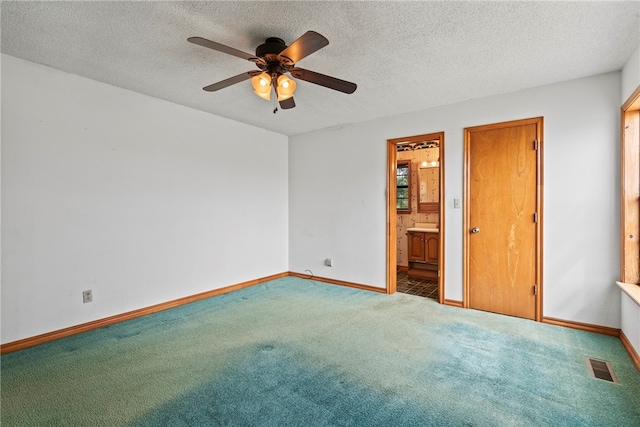 unfurnished bedroom with a textured ceiling, ensuite bathroom, ceiling fan, and carpet floors