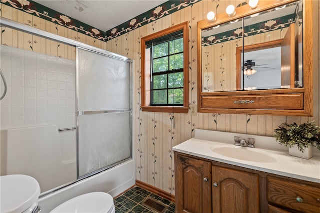 full bathroom featuring enclosed tub / shower combo, tile patterned floors, toilet, ceiling fan, and vanity