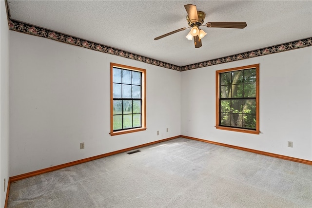 carpeted spare room featuring a textured ceiling and ceiling fan