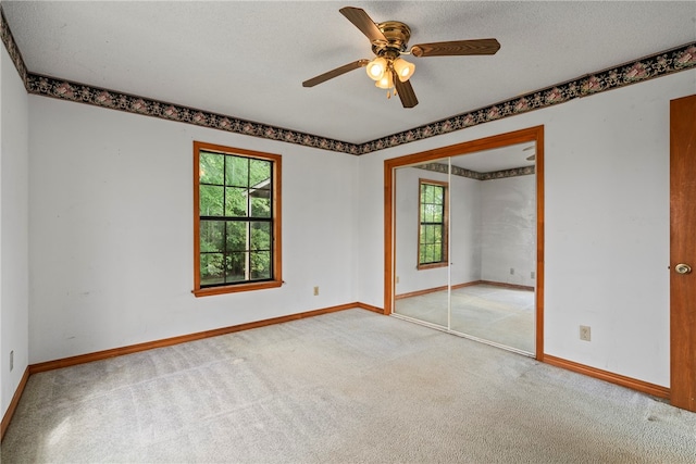 empty room featuring light colored carpet, a textured ceiling, and ceiling fan