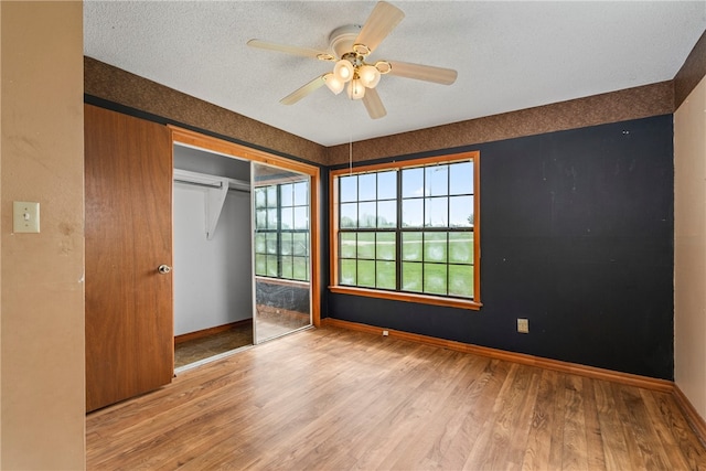 unfurnished bedroom with a closet, multiple windows, ceiling fan, and light hardwood / wood-style flooring