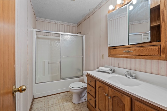 full bathroom featuring tile patterned floors, toilet, shower / bath combination with glass door, vanity, and a textured ceiling