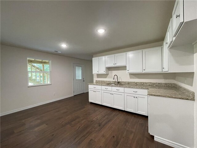 kitchen featuring sink, white cabinetry, light stone counters, and dark hardwood / wood-style floors