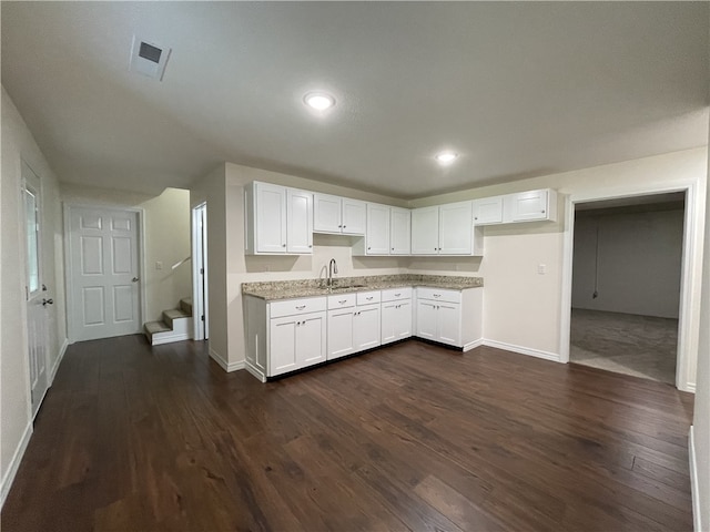 kitchen featuring sink, white cabinetry, dark hardwood / wood-style floors, and light stone countertops