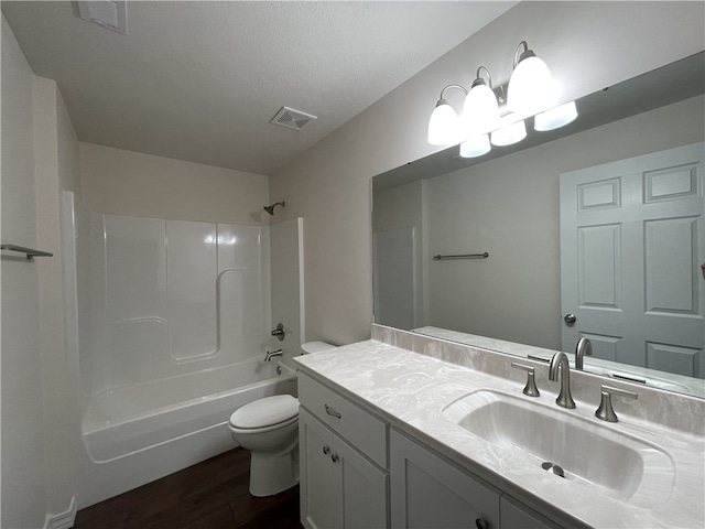 full bathroom with washtub / shower combination, wood-type flooring, toilet, vanity, and a textured ceiling