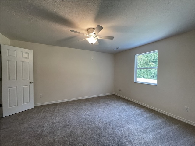 empty room featuring ceiling fan, a textured ceiling, and dark carpet