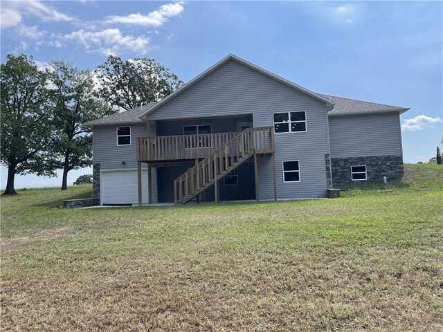 back of property with a lawn, a garage, and a wooden deck