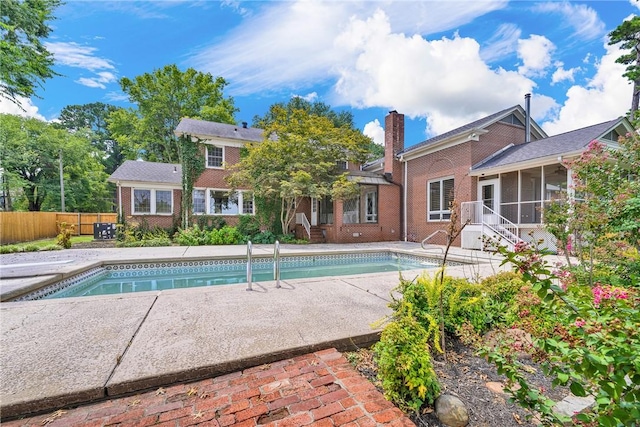 view of swimming pool featuring a fenced in pool, a patio, fence, and a sunroom