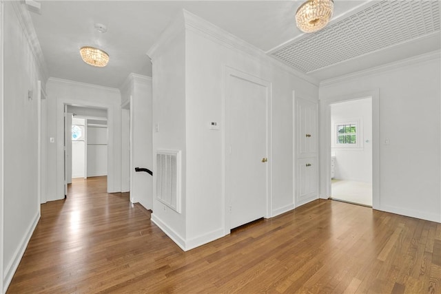 hall with visible vents, crown molding, baseboards, and wood finished floors