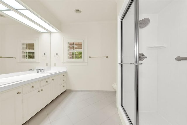 bathroom featuring baseboards, double vanity, a stall shower, a sink, and toilet