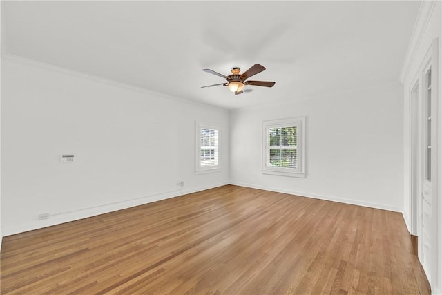 spare room with baseboards, light wood-style floors, ornamental molding, and a ceiling fan