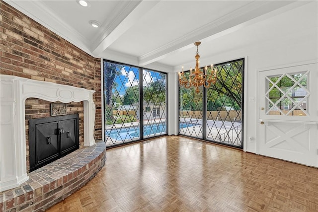 unfurnished living room featuring beam ceiling, a chandelier, a brick fireplace, and a wealth of natural light