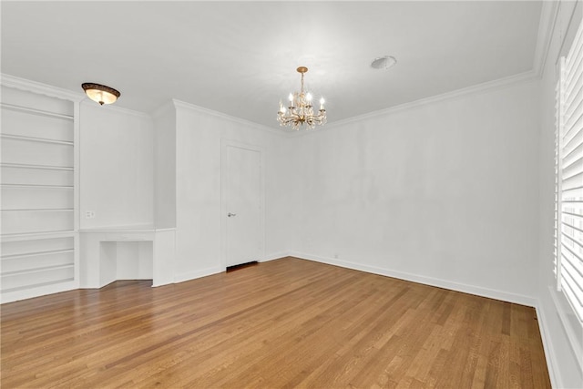 unfurnished room with a notable chandelier, built in features, light wood-type flooring, and crown molding