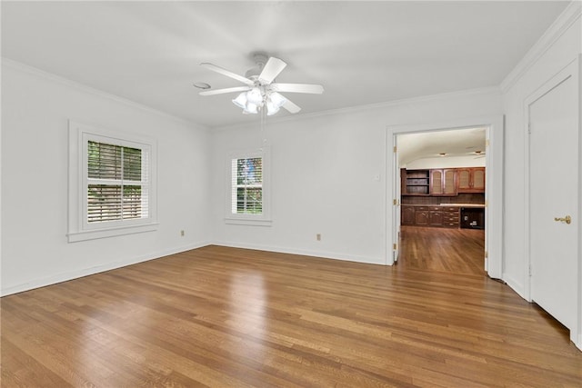 empty room with ceiling fan, wood finished floors, baseboards, and ornamental molding