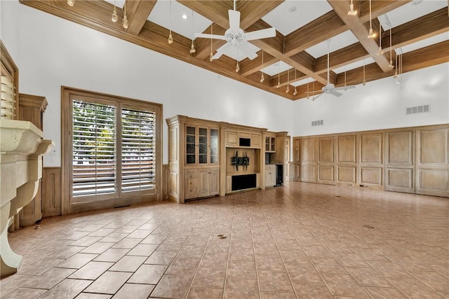 unfurnished living room featuring visible vents, ceiling fan, beamed ceiling, a towering ceiling, and coffered ceiling