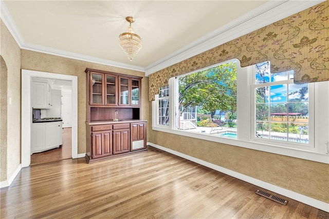 unfurnished dining area with baseboards, visible vents, light wood finished floors, and ornamental molding