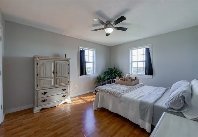 bedroom featuring ceiling fan, hardwood / wood-style floors, and multiple windows