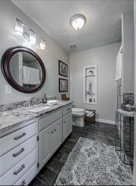 bathroom featuring vanity, toilet, tile patterned floors, and a textured ceiling