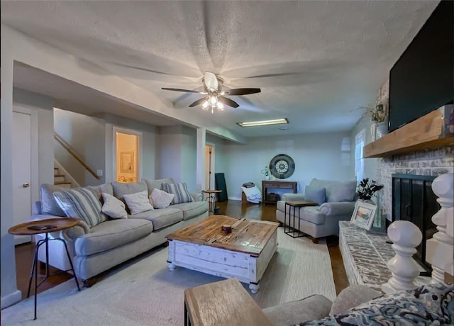 42 County Road 640, Green Forest, AR 72638 - living room with stairway, wood finished floors, a large fireplace, a textured ceiling, and ceiling fan