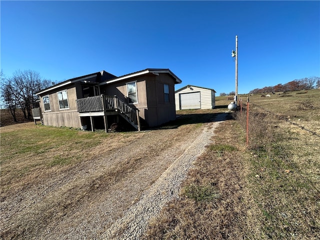 exterior space with an outdoor structure, a lawn, a rural view, a garage, and a deck