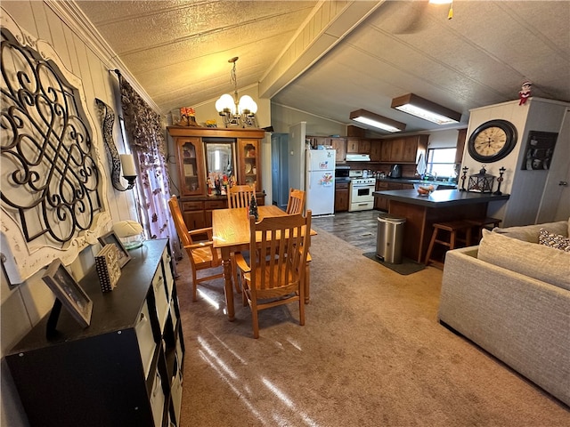 dining room featuring sink, dark colored carpet, a chandelier, and vaulted ceiling