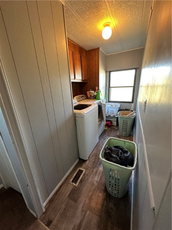 laundry area featuring crown molding, cabinets, independent washer and dryer, and dark hardwood / wood-style flooring