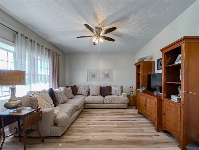 living room featuring ceiling fan, a textured ceiling, and light hardwood / wood-style flooring