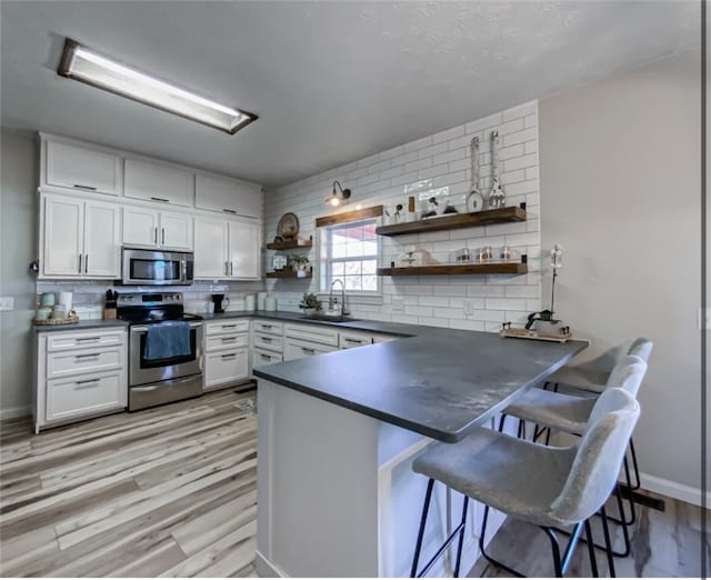 kitchen featuring backsplash, a breakfast bar, kitchen peninsula, and appliances with stainless steel finishes