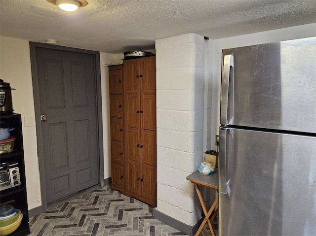 kitchen with stainless steel refrigerator and a textured ceiling