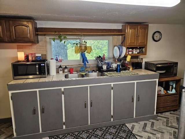 kitchen with tile countertops, dark brown cabinets, and sink