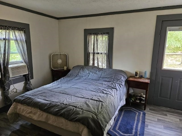 bedroom featuring wood-type flooring, a textured ceiling, cooling unit, and crown molding