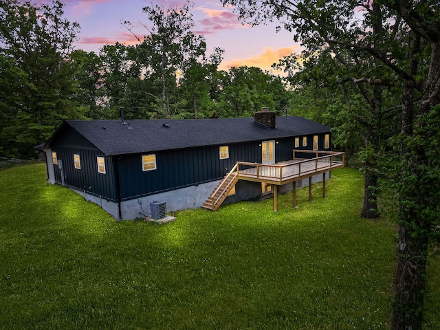 back house at dusk featuring a yard, a deck, and central air condition unit