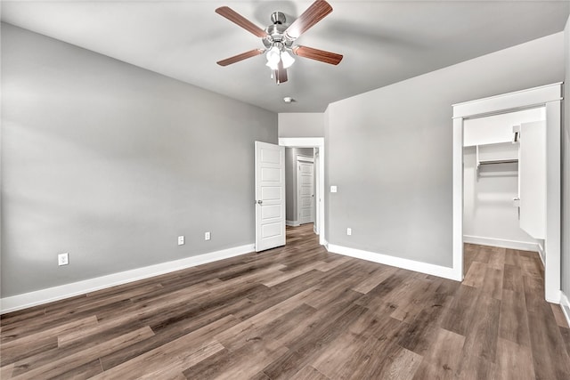 unfurnished bedroom with dark hardwood / wood-style flooring, a closet, a spacious closet, and ceiling fan