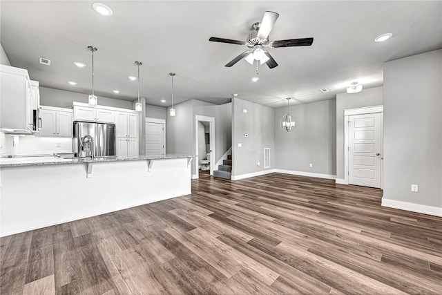 unfurnished living room featuring dark wood-type flooring and ceiling fan with notable chandelier