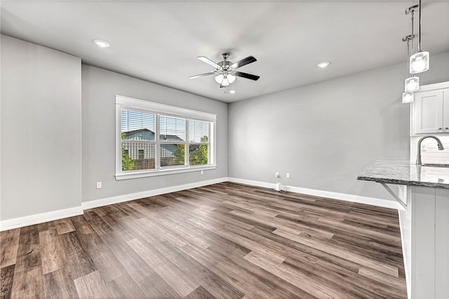 unfurnished living room featuring sink, hardwood / wood-style floors, and ceiling fan