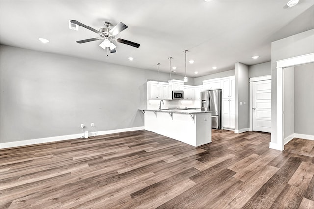 kitchen featuring white cabinetry, stainless steel appliances, decorative light fixtures, and dark hardwood / wood-style floors