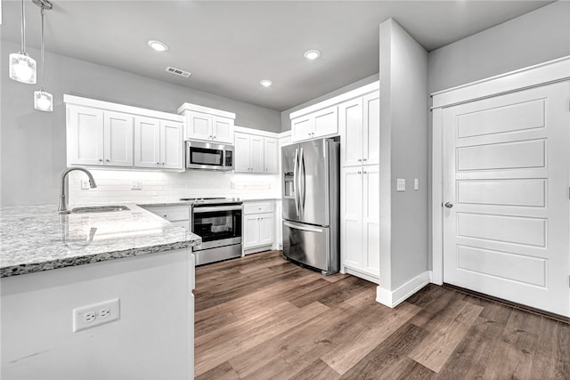 kitchen featuring appliances with stainless steel finishes, white cabinets, sink, and hanging light fixtures