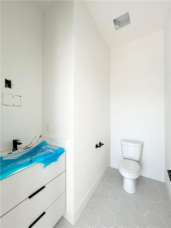 200 NW 9th St, Bentonville, AR 72712 - bathroom featuring toilet, baseboards, tile patterned floors, and vaulted ceiling